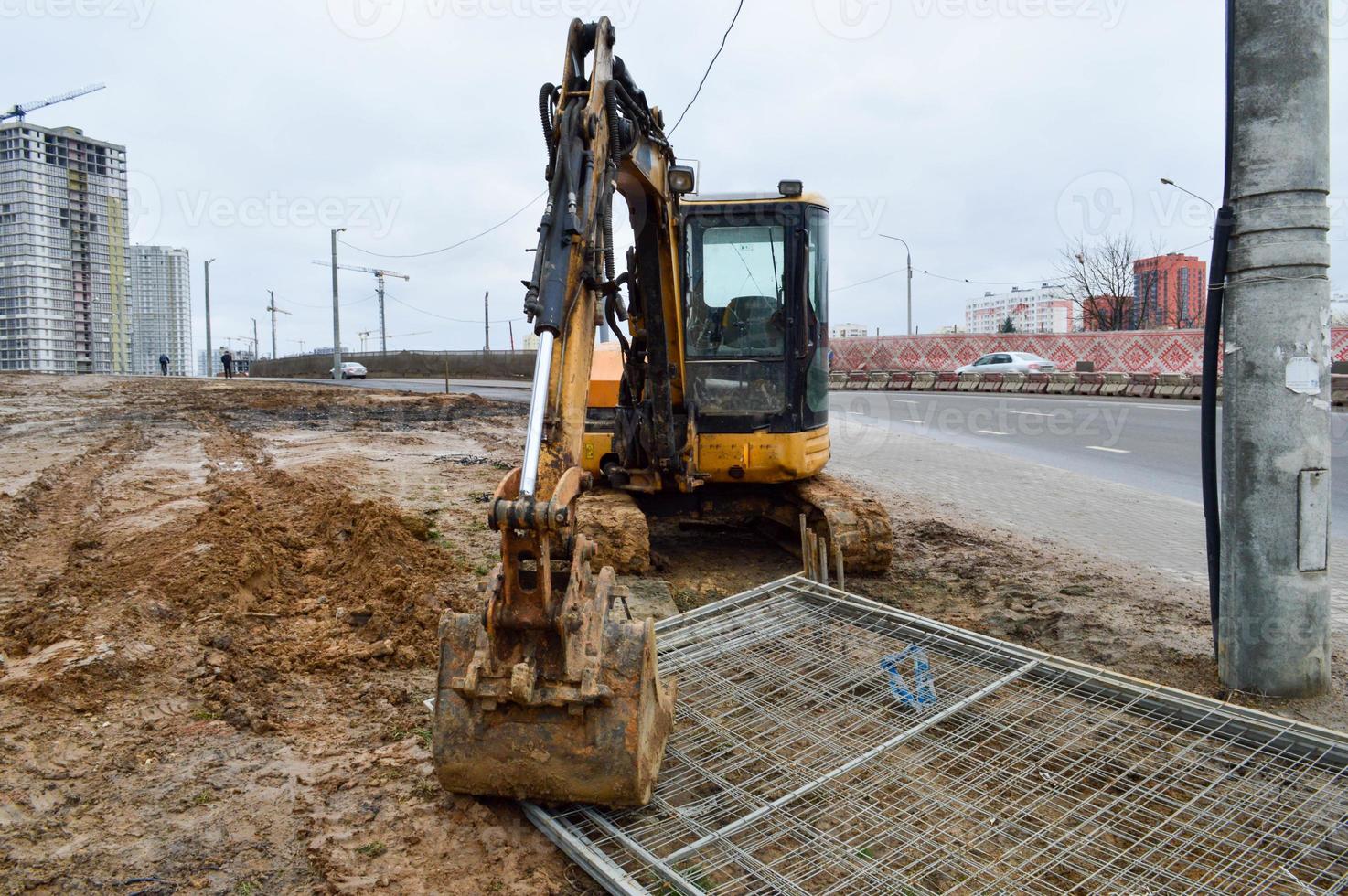 Big bright yellow powerful industrial heavy excavator tractor, bulldozer, specialized construction equipment for road repair during the construction of a new micro-district in a big city photo