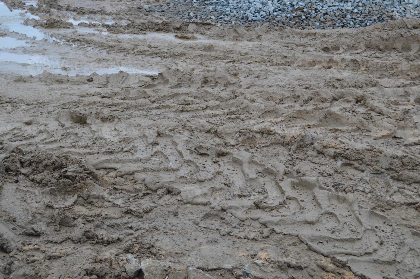 Texture of a dirty bad dirt road dirt road with puddles and clay drying mud with cracks and ruts. Off-road. The background photo