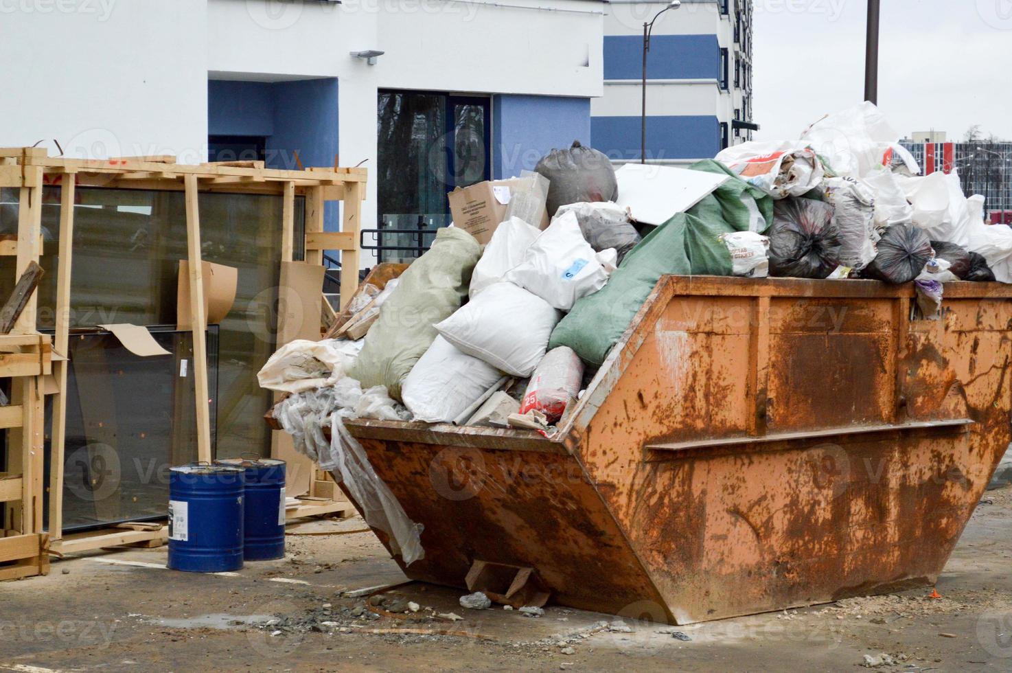 gran cubo de basura industrial de hierro. un lío de basura con suciedad, mala seguridad, condiciones insalubres y contaminación ambiental en un sitio de construcción industrial foto