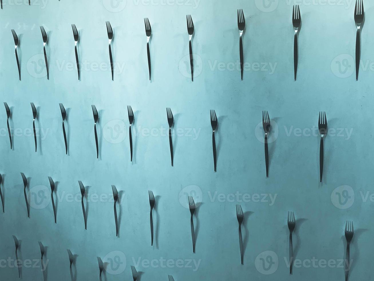 patrón de una variedad de tenedores de metal, cubiertos en la pared sobre un fondo azul. textura foto