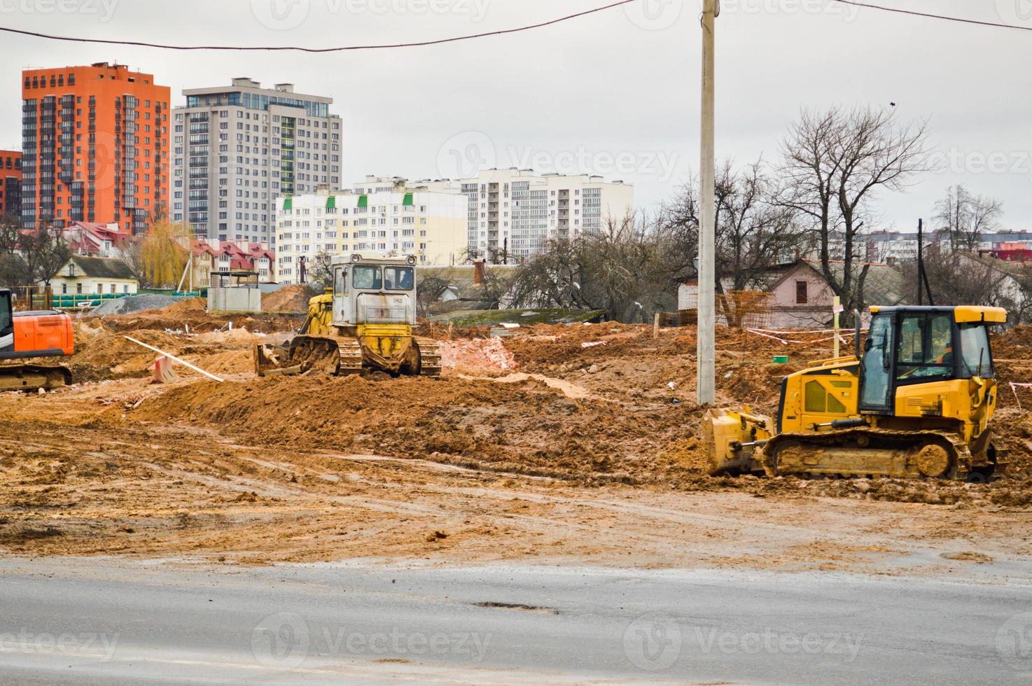 Muchos potentes equipos industriales pesados de construcción especializados de excavadoras de tractores y excavadoras reparan carreteras durante la construcción de un nuevo microdistrito en una gran ciudad foto