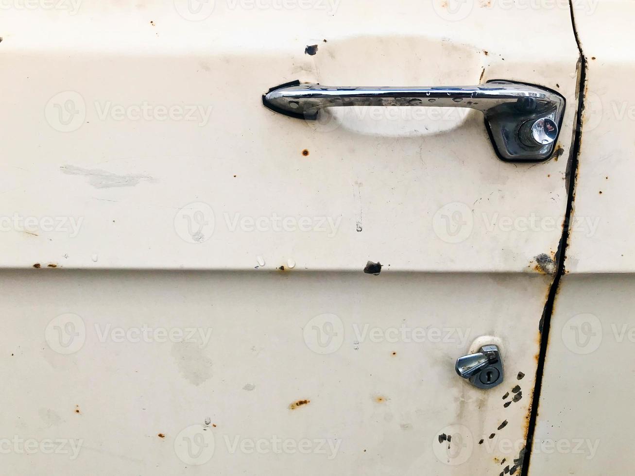 An old retro vintage hipster rusty oxidized chrome metal silver door knob with a retro button for an antiquan white American passenger car from the 60s, 70s, 80s, 90s, 2000s photo