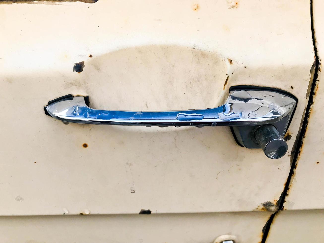 An old retro vintage hipster rusty oxidized chrome metal silver door knob with a retro button for an antiquan white American passenger car from the 60s, 70s, 80s, 90s, 2000s photo