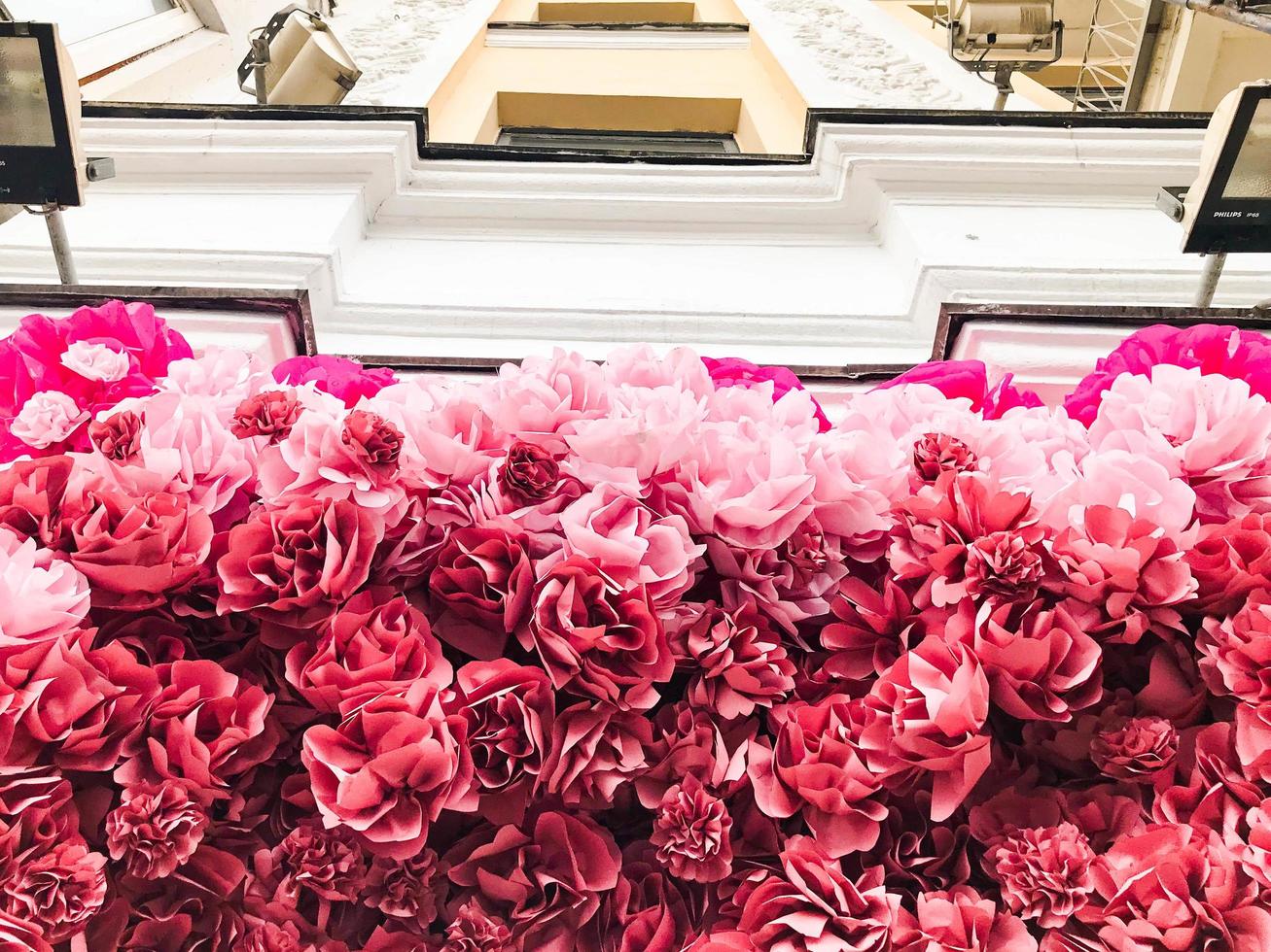 The decoration of the house, the facade of the building with red pink roses and peony flowers. The background photo