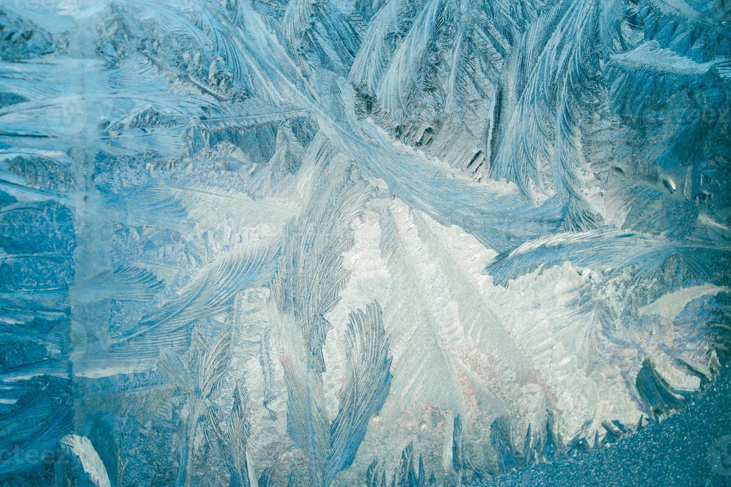 Winter frosty patterns on glass. Christmas festive background. Shiny ice crystals on window. photo