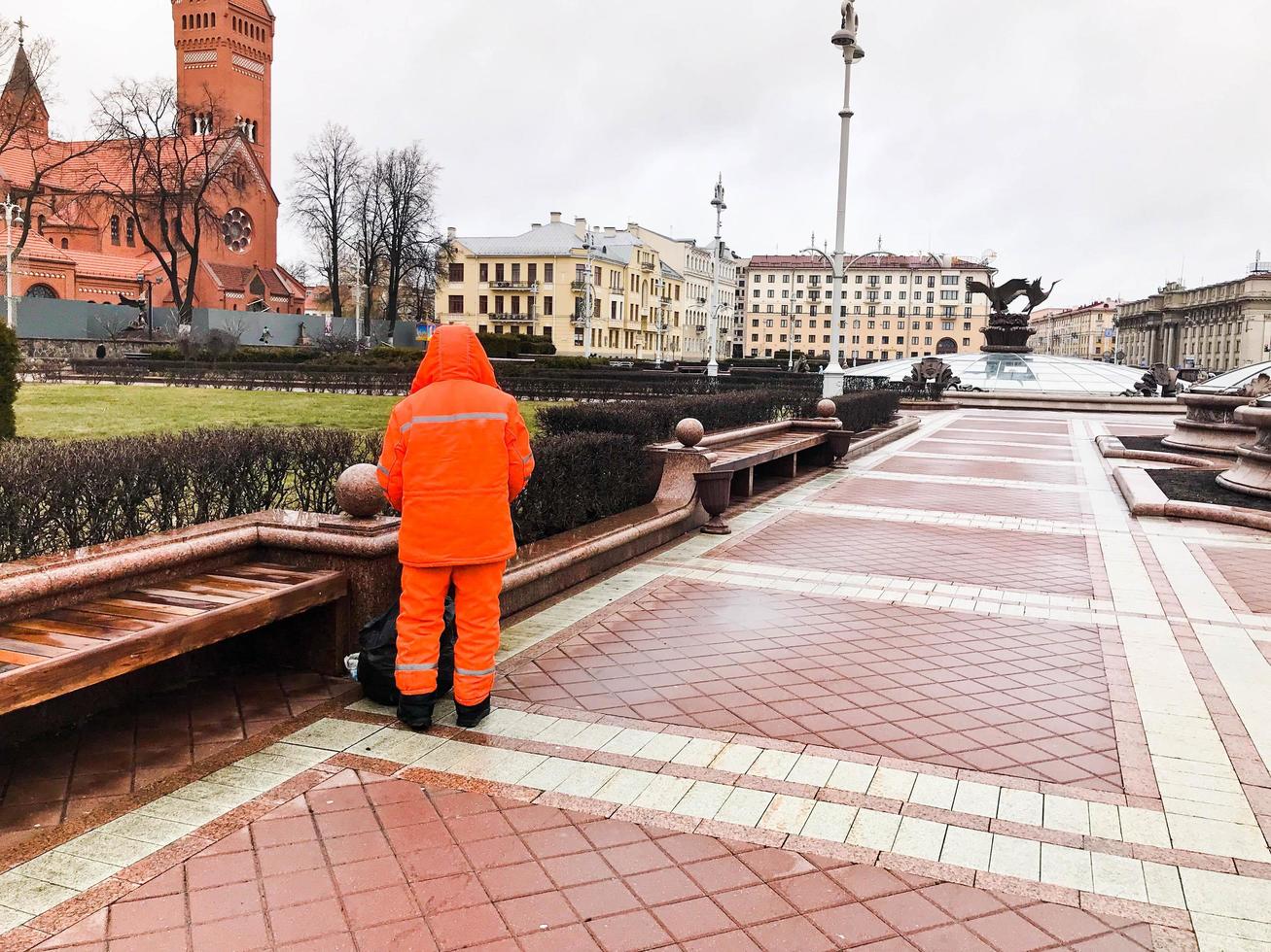 Male working cleaner in orange overalls wearing robe clothes working cleans the streets of the city photo