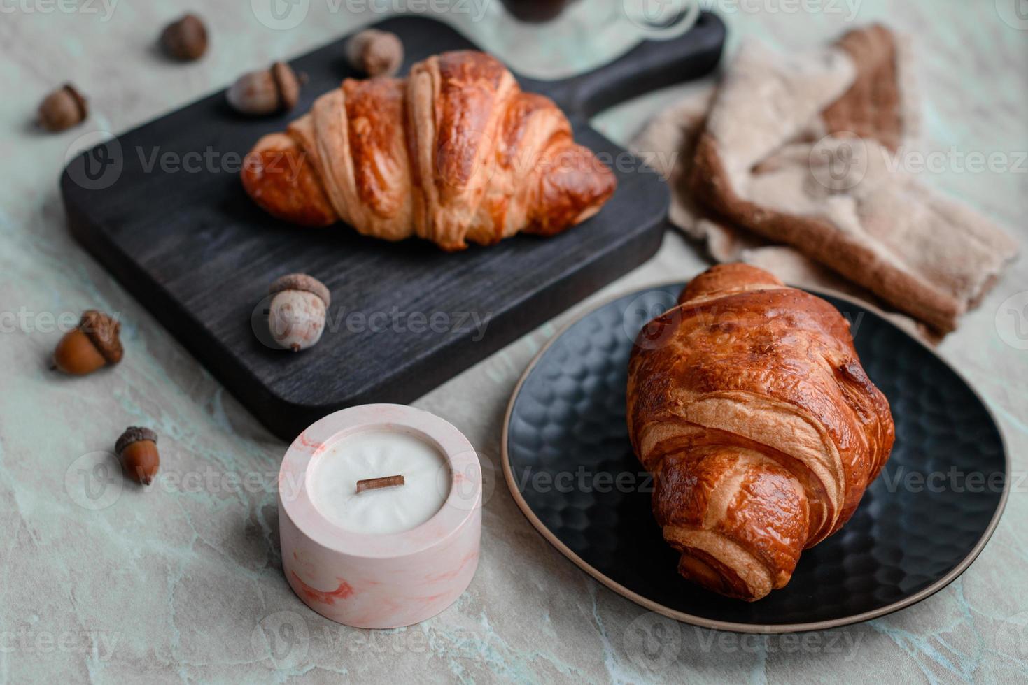 Delicious crispy croissant with chocolate with a cup of invigorating coffee on a light concrete background photo