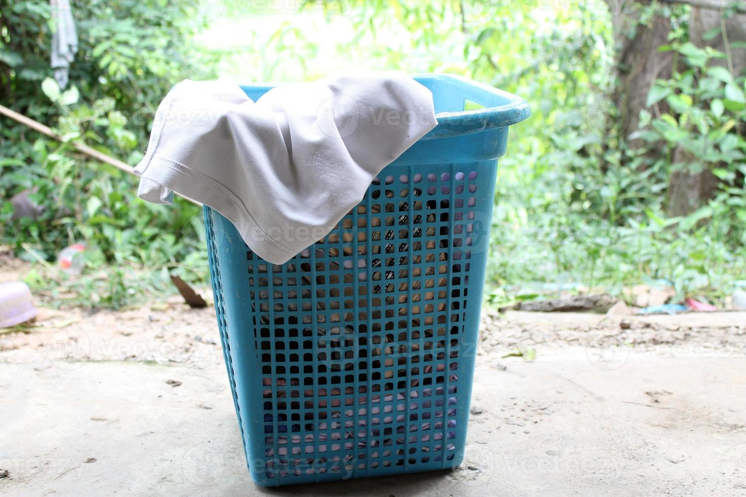 Pile of clothes overflow plastic laundry basket for washing photo