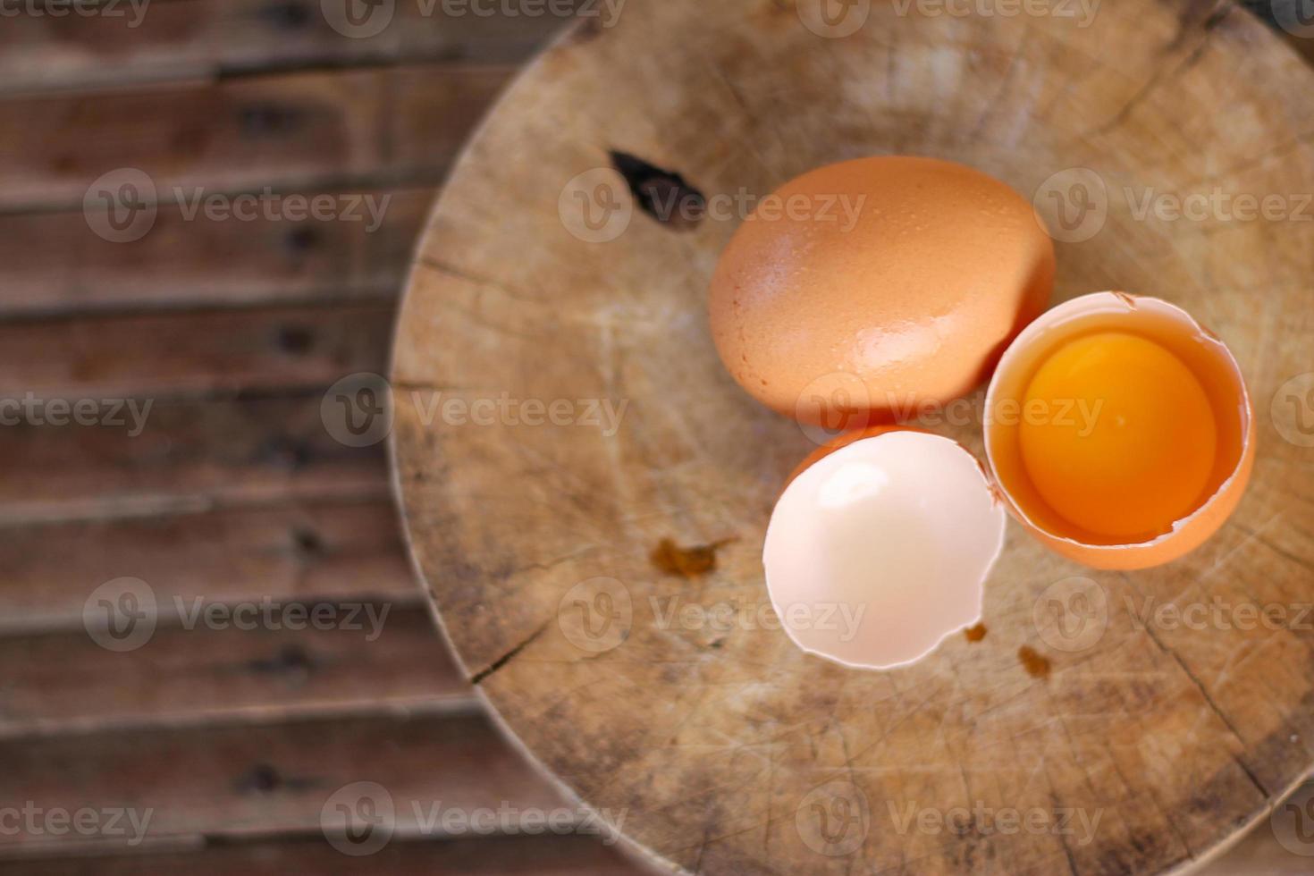 Brown eggs on a wooden chopping board There is a yolk in the egg shell. The brown egg has a drop of water because it is removing from the refrigerator. photo