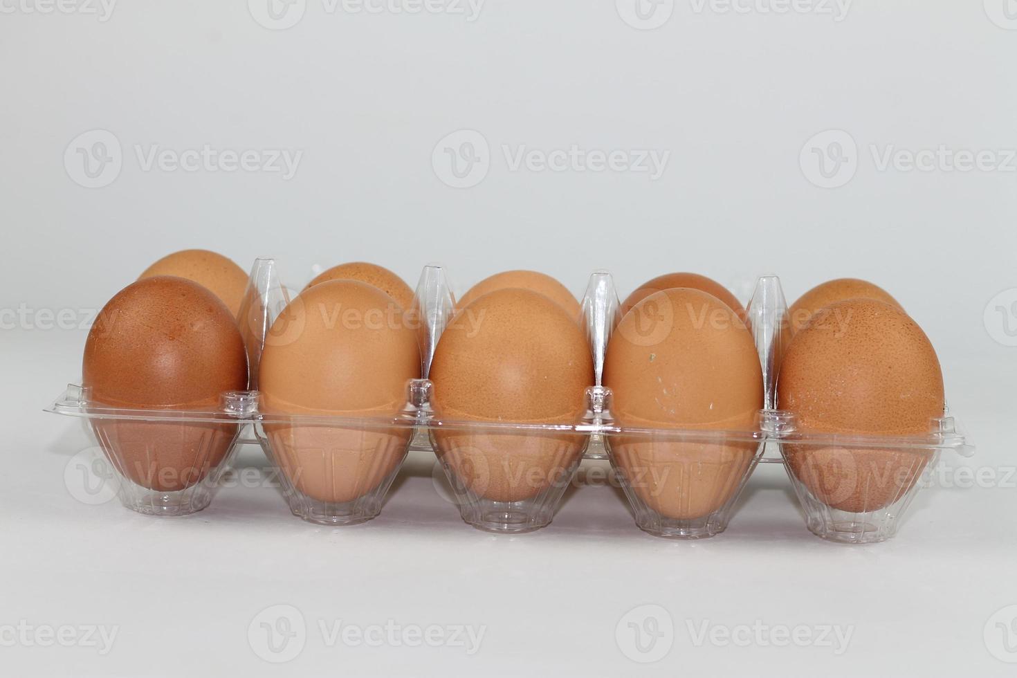 Close-up view of raw chicken eggs in egg box on white white background photo