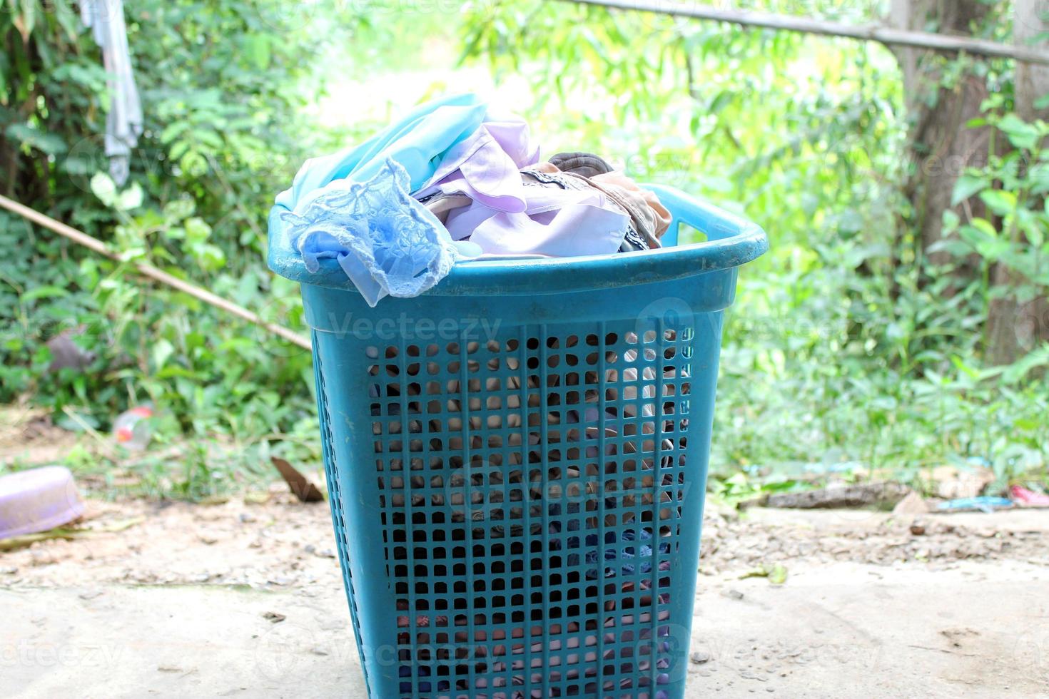 Pile of clothes overflow plastic laundry basket for washing photo