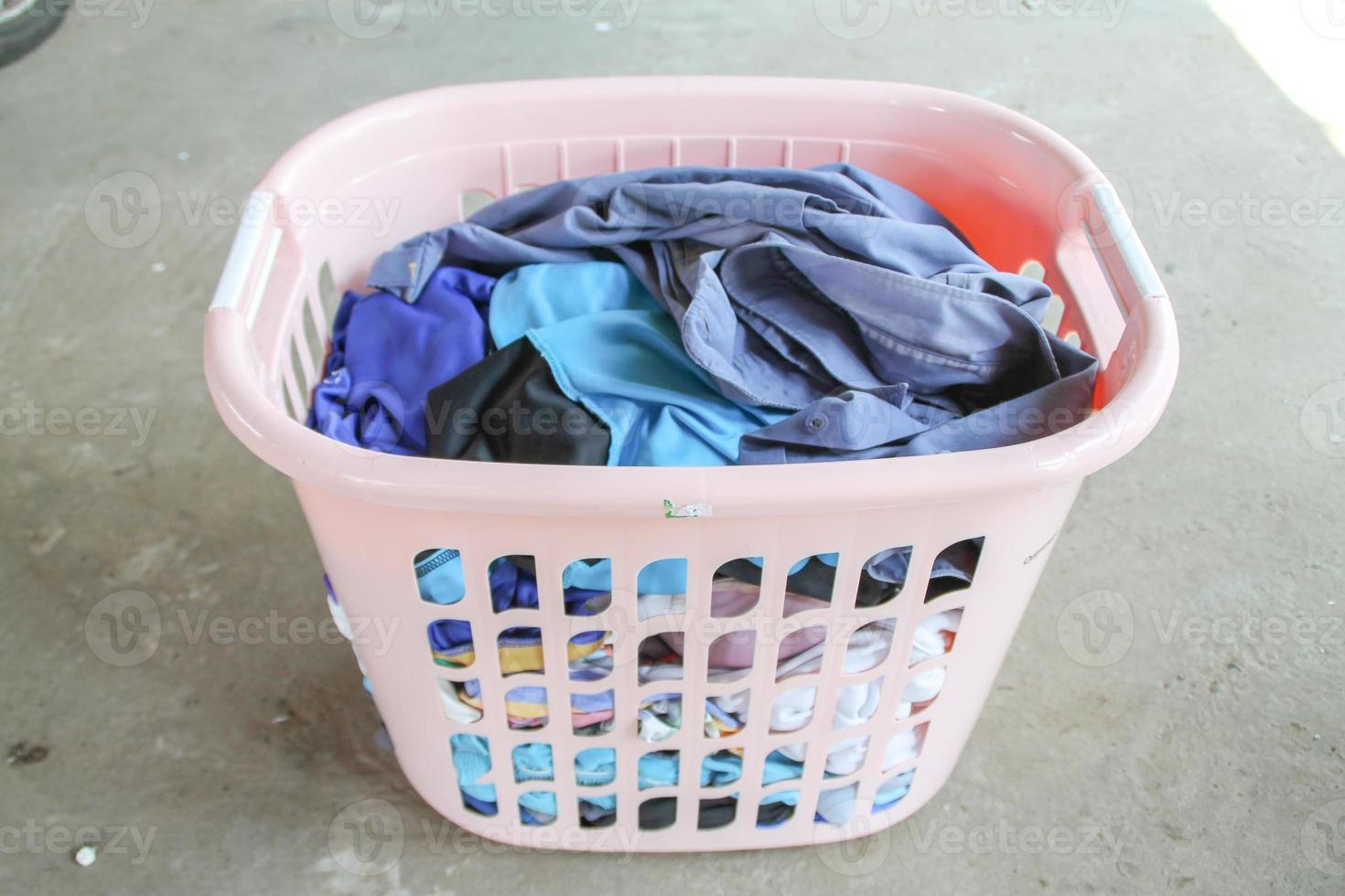 Pink Basket with dirty laundry on floor. photo