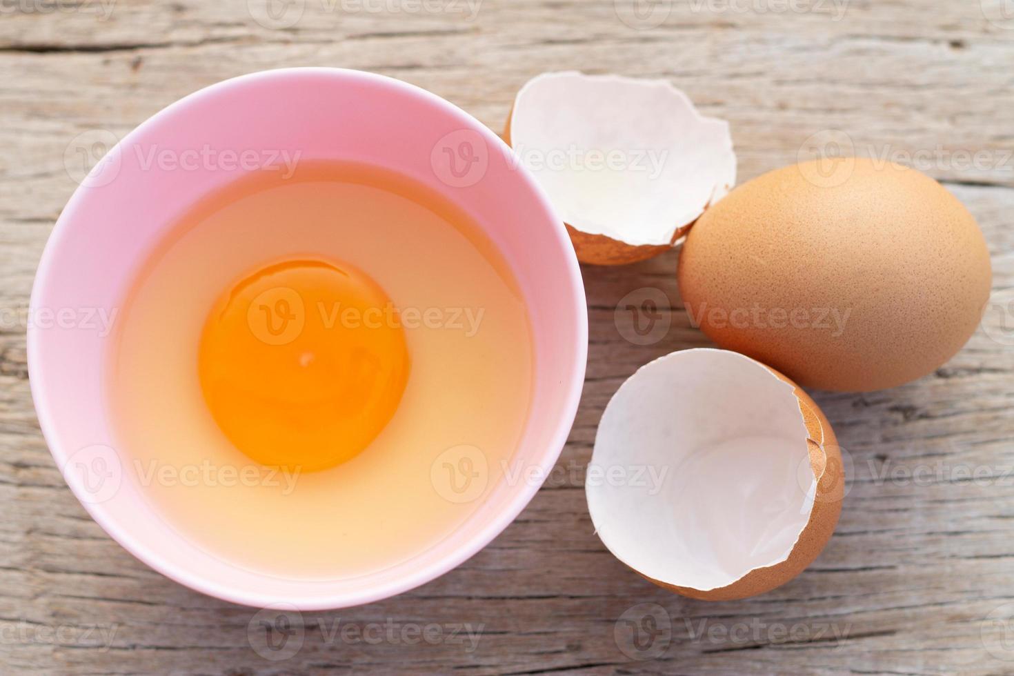 Broken egg shells and eggs on bowl, raw egg in small bowl at wooden background menu and recipe. photo