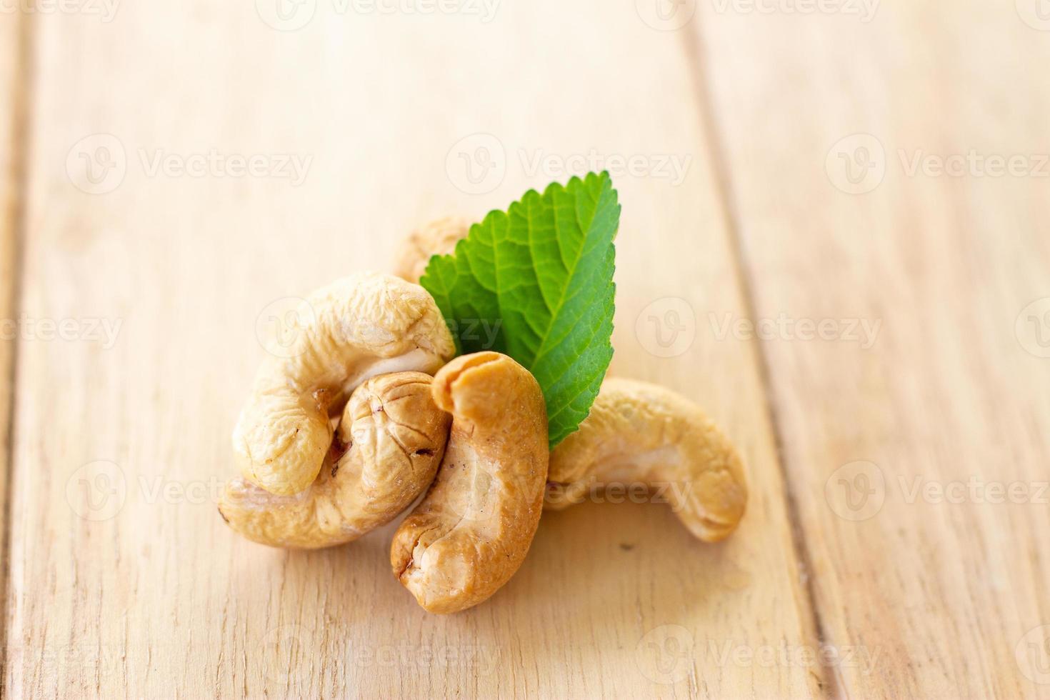 many cashew nut with green leaf on wooden table photo