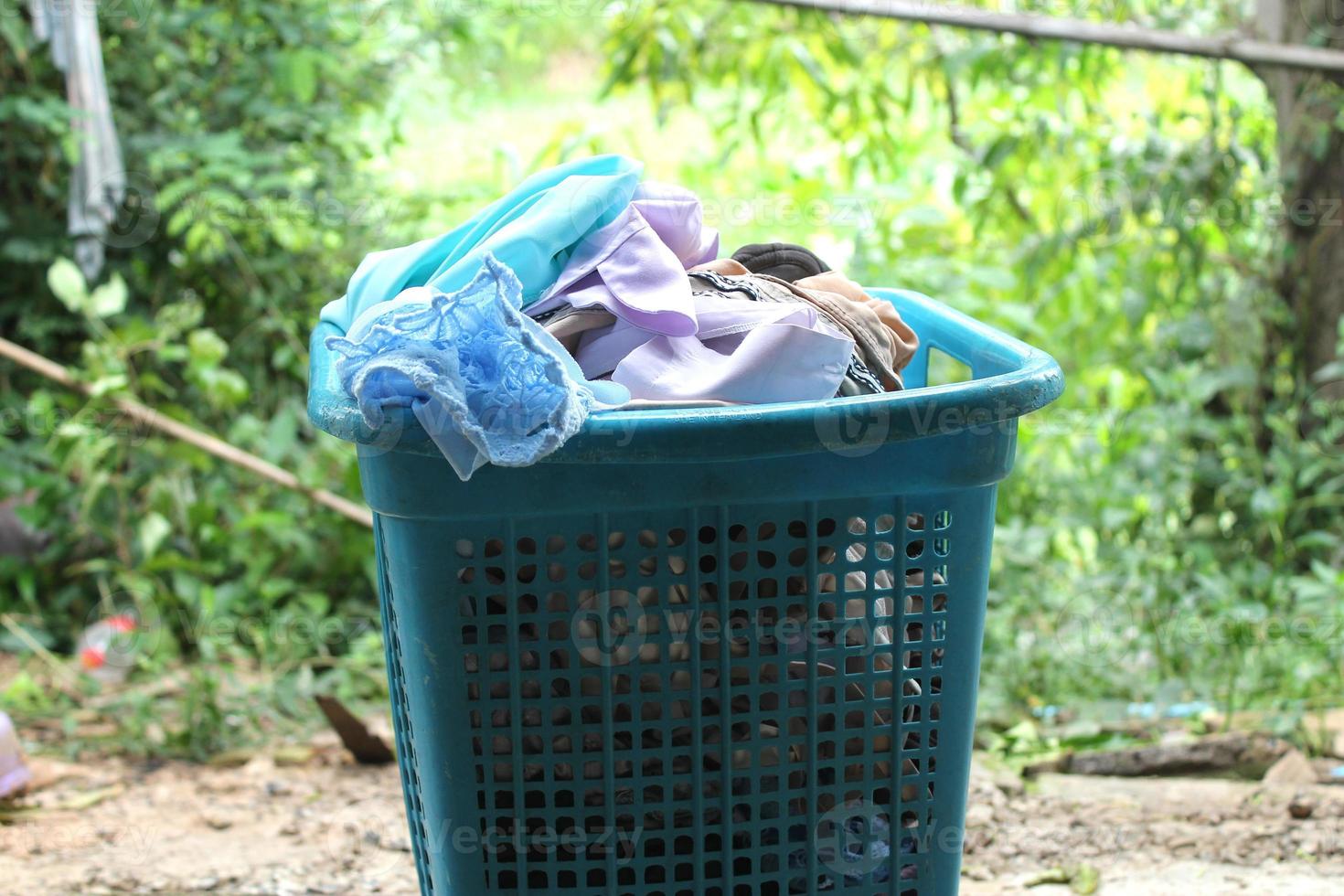 Pile of clothes overflow plastic laundry basket for washing photo