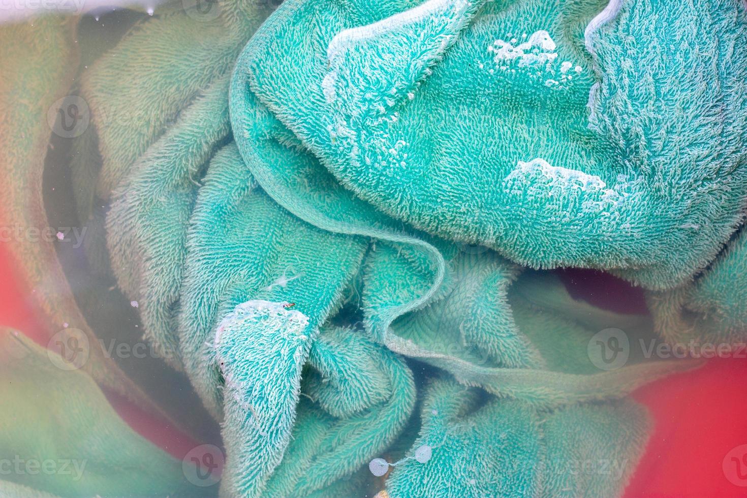 Soak the green towel in the water before washing. photo