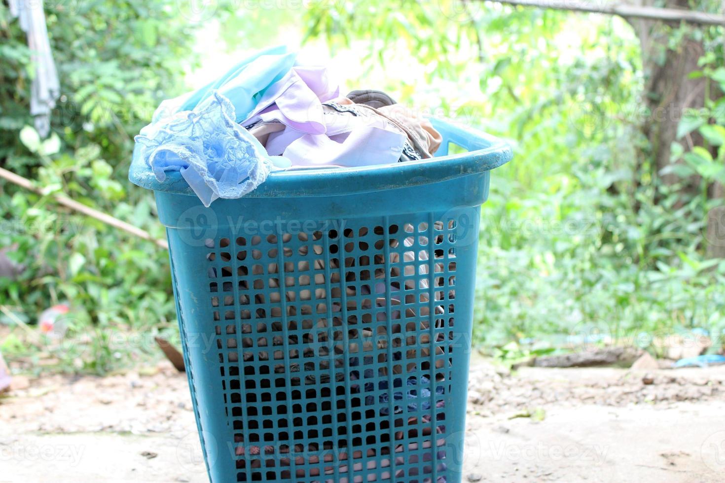 Pile of clothes overflow plastic laundry basket for washing photo