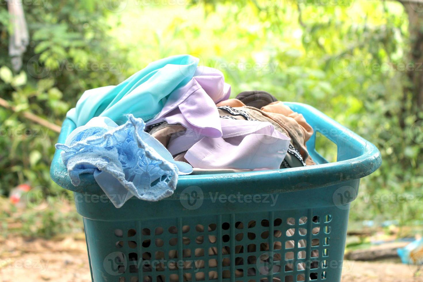 Pile of clothes overflow plastic laundry basket for washing photo