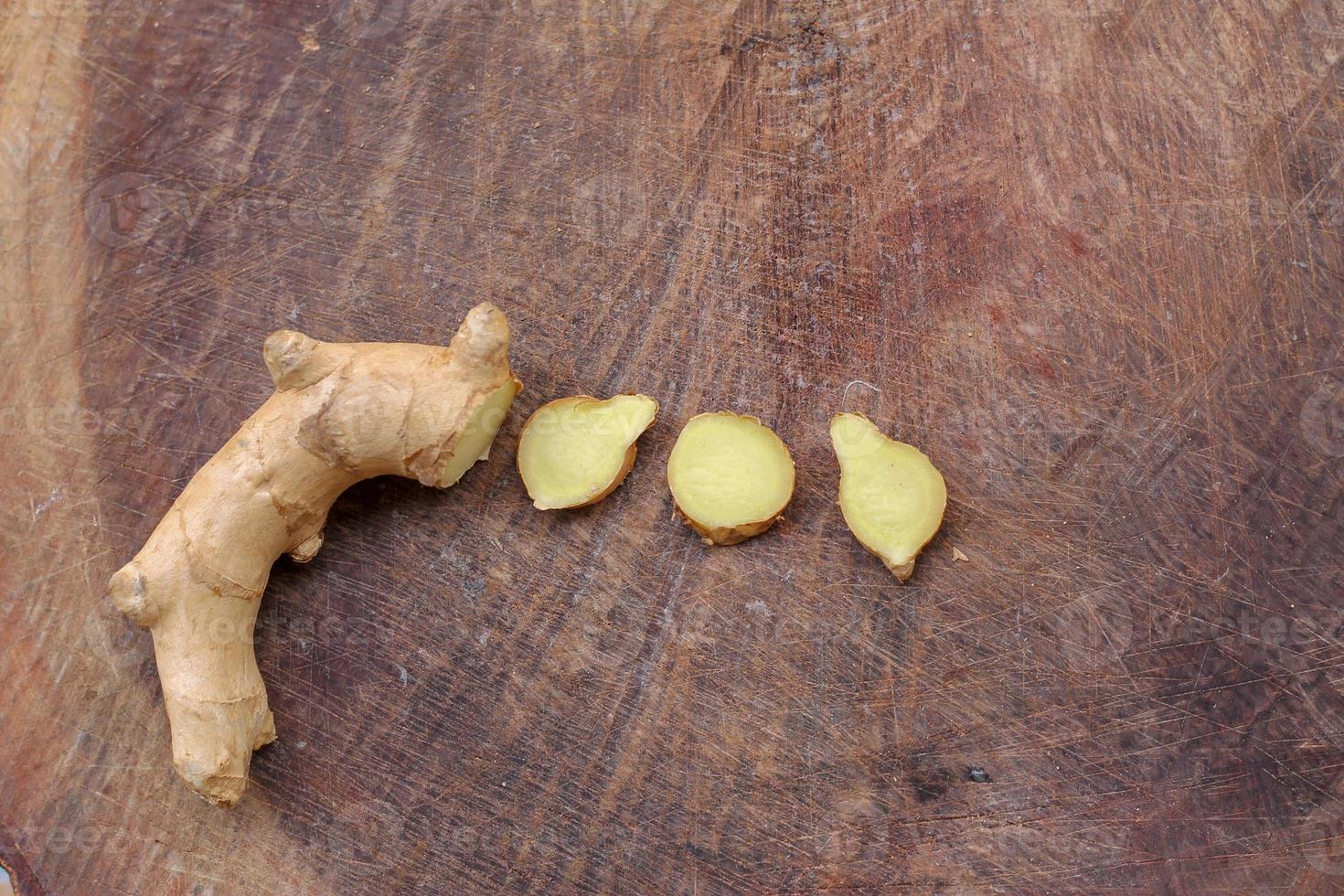 Ginger root sliced on wooden background photo