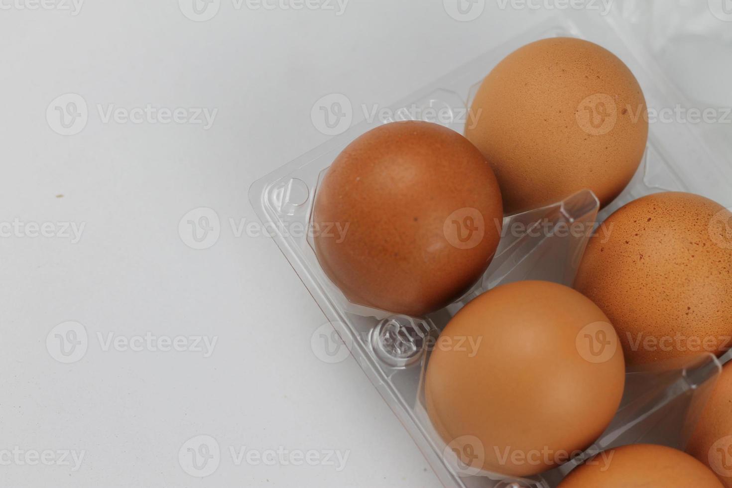 Close-up view of raw chicken eggs in egg box on white white background photo