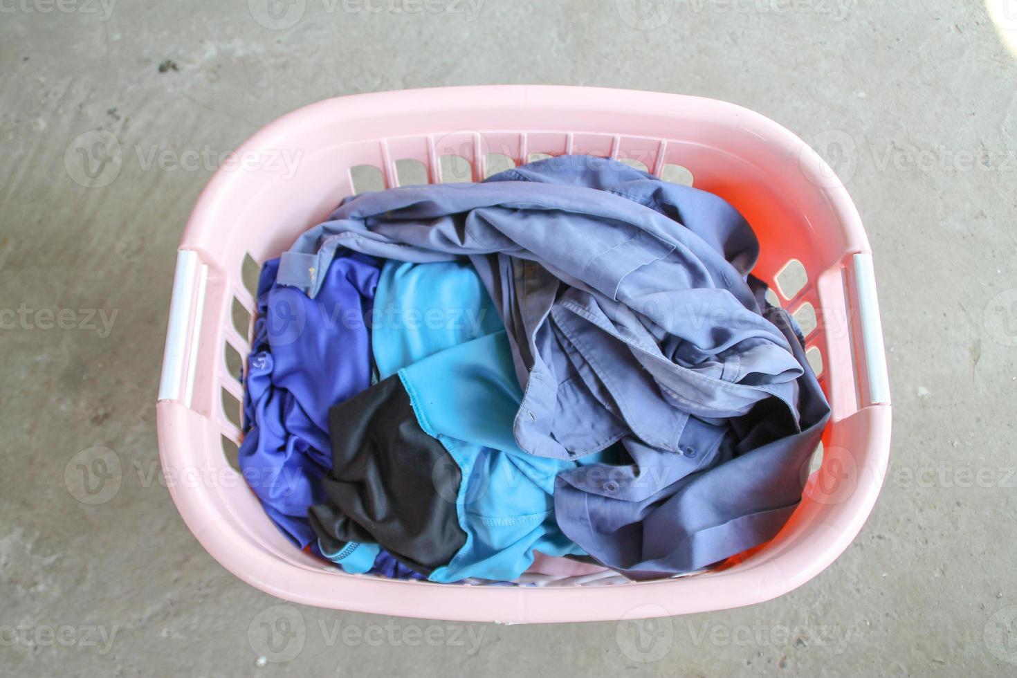 Pink Basket with dirty laundry on floor. photo