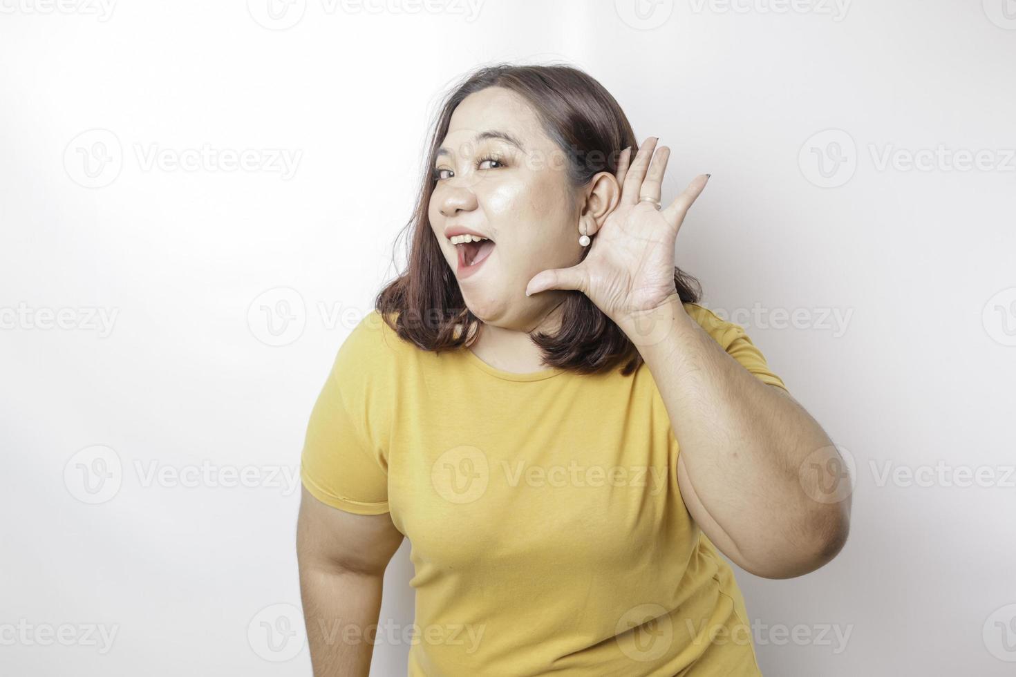 Young beautiful Asian big sized woman wearing a yellow shirt shouting and screaming loud with a hand on her mouth. communication concept. photo