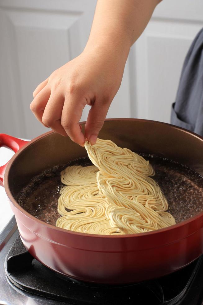 Boiling Korean Instant Noodle Spicy Ramyun on Sauce Pan, Add Noodle to the Pan, Home Cooking Activity photo