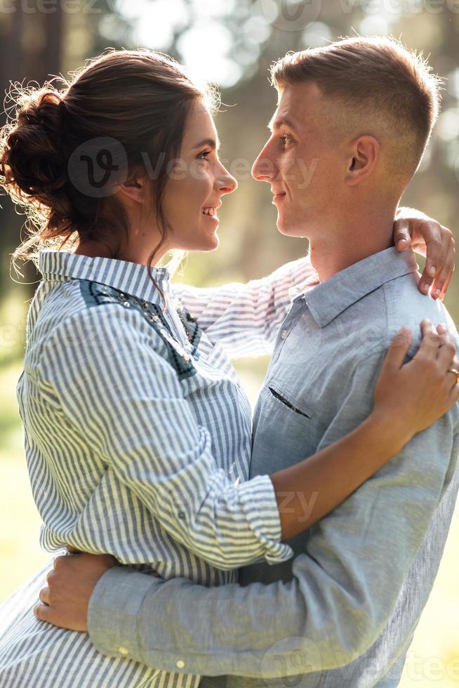 Cheerful young woman and man are hugging outdoors in summer park. Dating and romantic vacation. couple in love gently looking at each other on sunny day. Love and relationships between young people photo