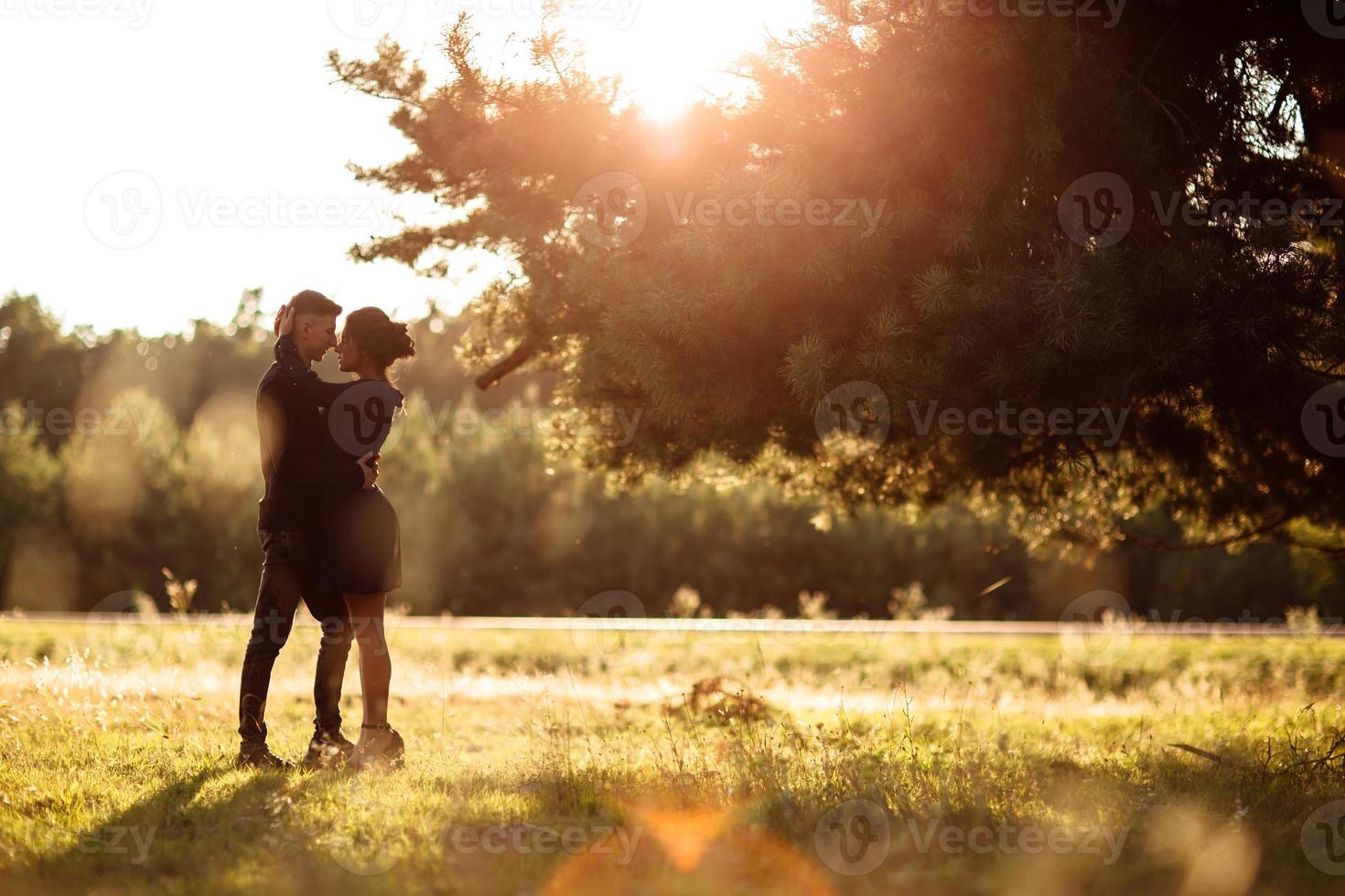 joven pareja enamorada caminando en el parque de verano tomados de la mano. mujer y hombre vestidos de negro tienen una cita al aire libre al atardecer. relación romántica. día de San Valentín foto