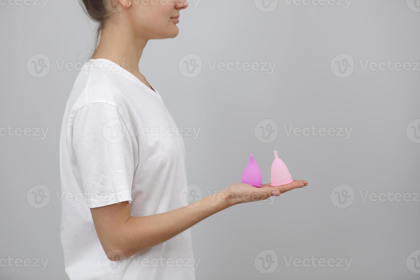 close up of woman holding in her hands different kinds of pink and purple menstrual cups. woman's choice. Gynecology concept photo