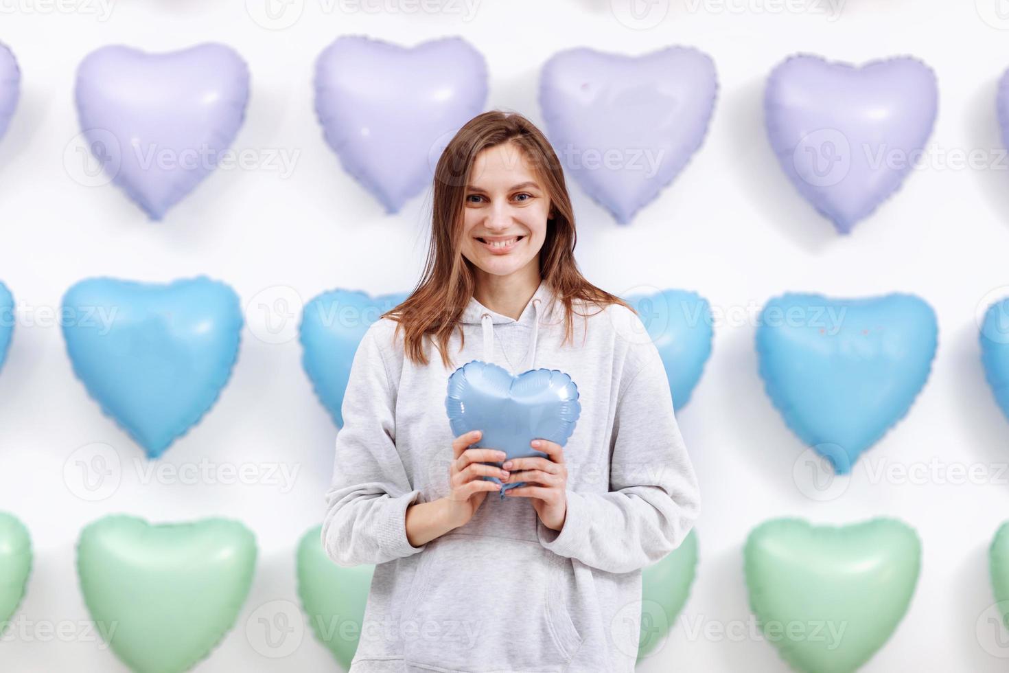 The woman holds the blue balloon in the form of a heart on many hearts background. valentines day. selective focus photo