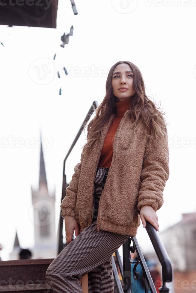 Fashion style portrait. beautiful stylish girl with long hair walks in the city. Portrait of attractive girl on the street. Spring or fall day. selective focus. photo