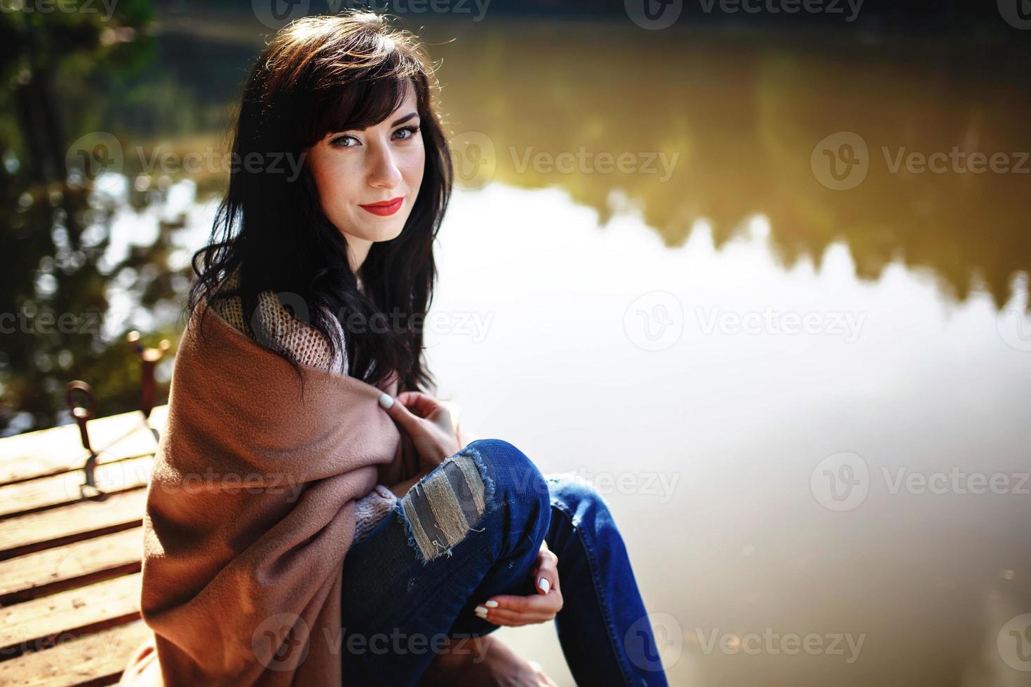 Beautiful girl with long brunette hair sitting on the bridge. nature photo