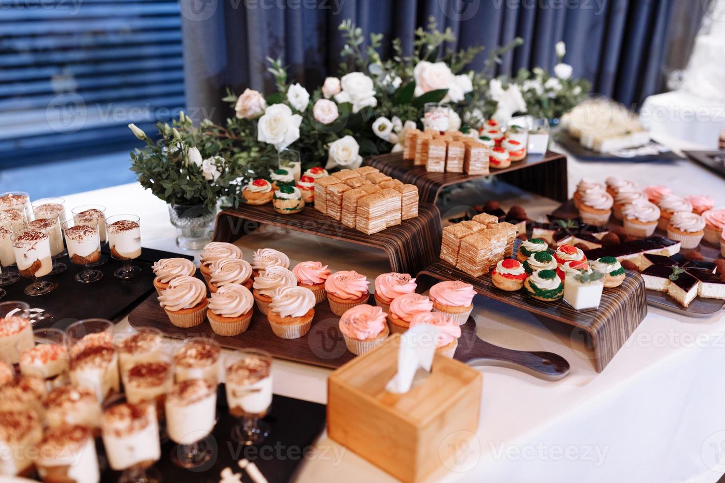 barra de dulces decorada con un delicioso buffet dulce con cupcakes, canutillos, dulzura y flores, y otros postres, dulces, mesa de postres para una boda o fiesta de cumpleaños. foto