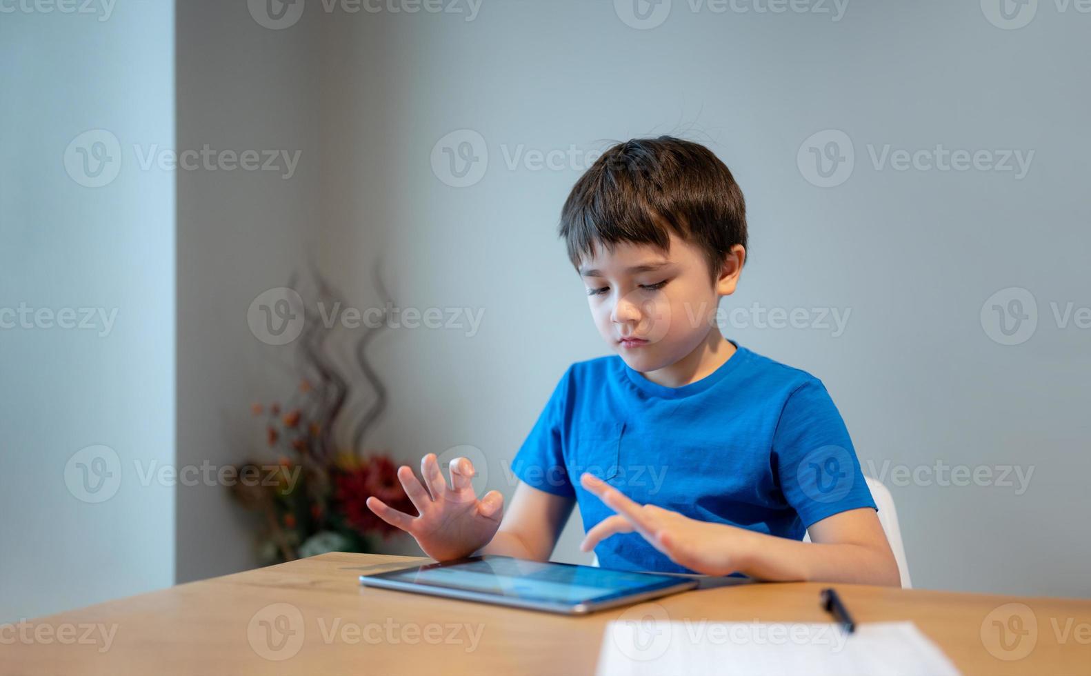School Kid learning online class room at home, Child using tablet for homework, Young boy studying online video call, E-learning or Homeschooling education concept photo