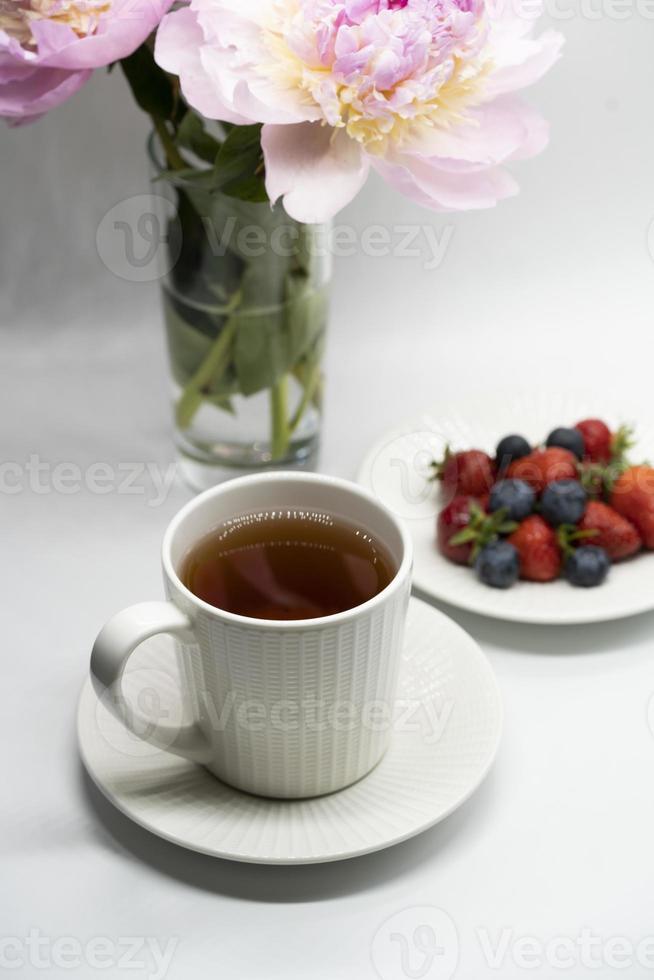 Cup of tea, peony and berries photo