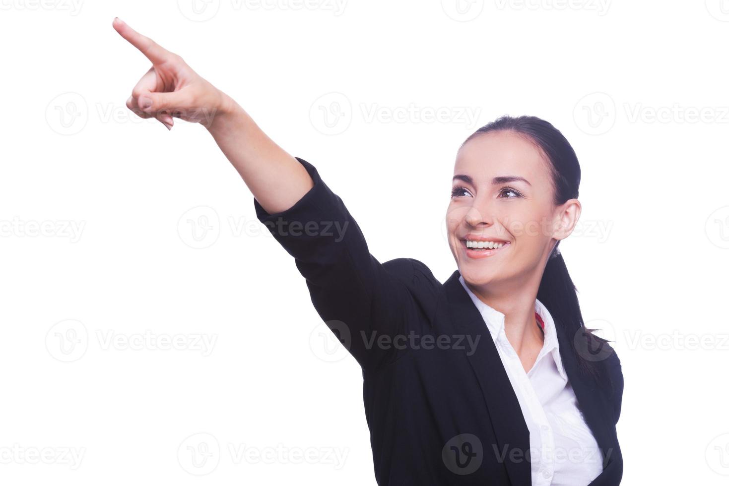 mire allí a una joven feliz con ropa formal señalando hacia otro lado y sonriendo mientras está de pie aislada en blanco foto