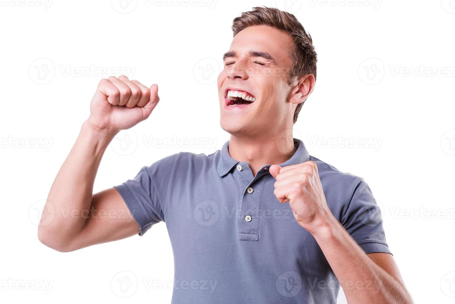 I am so happy Happy young man keeping eyes closed and gesturing while standing isolated on white background photo