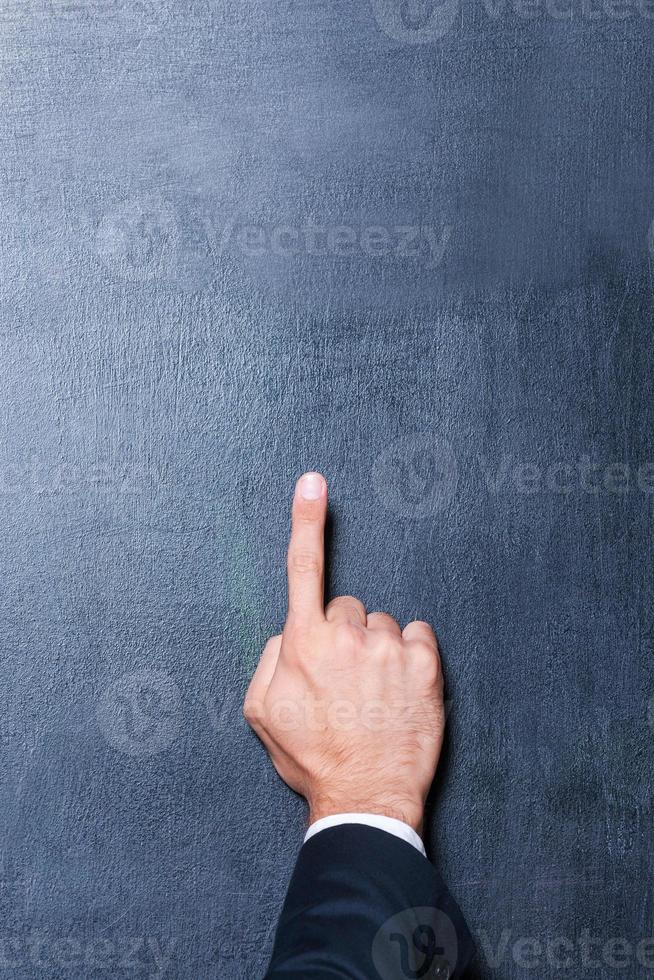 Look up Close-up of human hand pointing copy space against blackboard photo