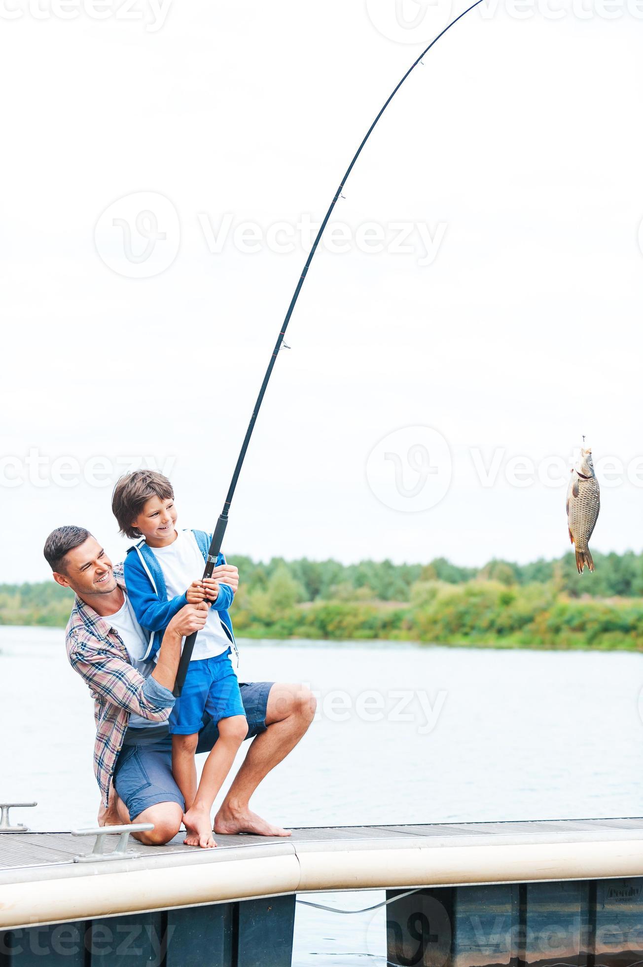 It is a big fish Father and son stretching a fishing rod with fish