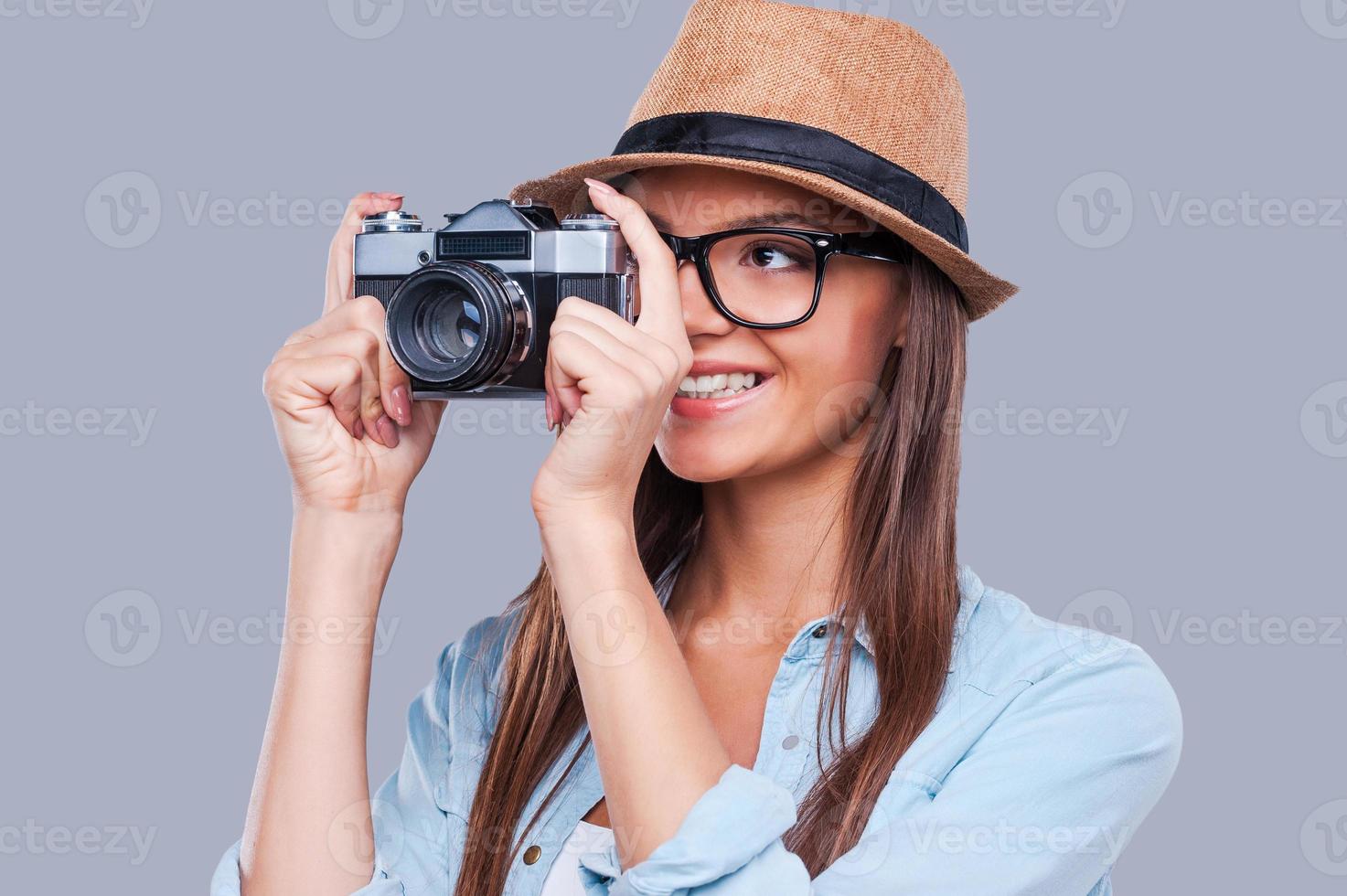 Be creative Creative young girl taking a photograph and smiling while standing against grey background photo