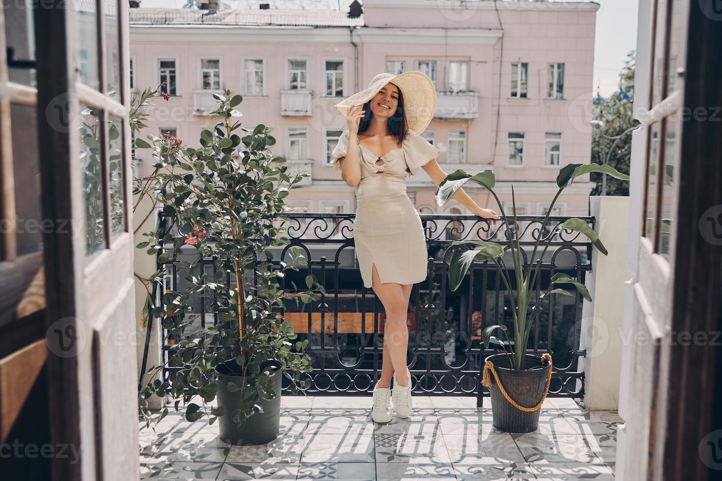 Full length of happy young woman in elegant hat relaxing on the balcony photo