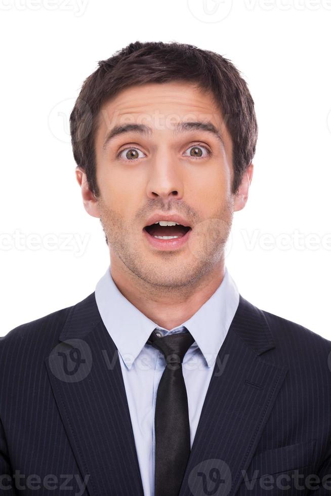 What a surprise Surprised young man in formalwear staring at camera and keeping mouth open while standing against grey background photo