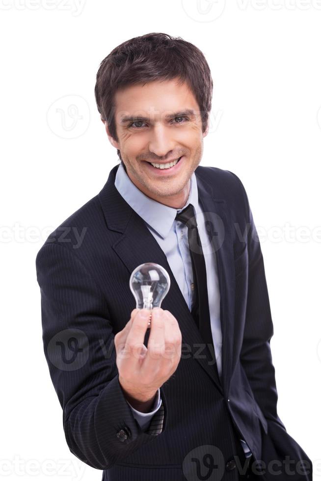 Got idea Cheerful young man in formalwear stretching out hand with light bulb and smiling while standing isolated on white background photo