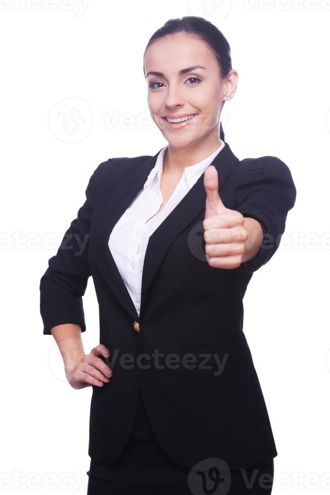 buen trabajo mujer joven feliz en ropa formal mostrando su pulgar hacia arriba y sonriendo mientras está de pie aislado en blanco foto