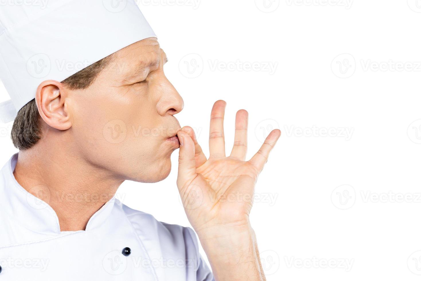 This meal is just perfect Side view of confident mature chef in white uniform keeping eyes closed and gesturing while standing against white background photo