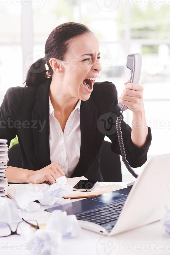 I want that report now Furious young businesswoman in formalwear shouting at the telephone while sitting at her working place photo