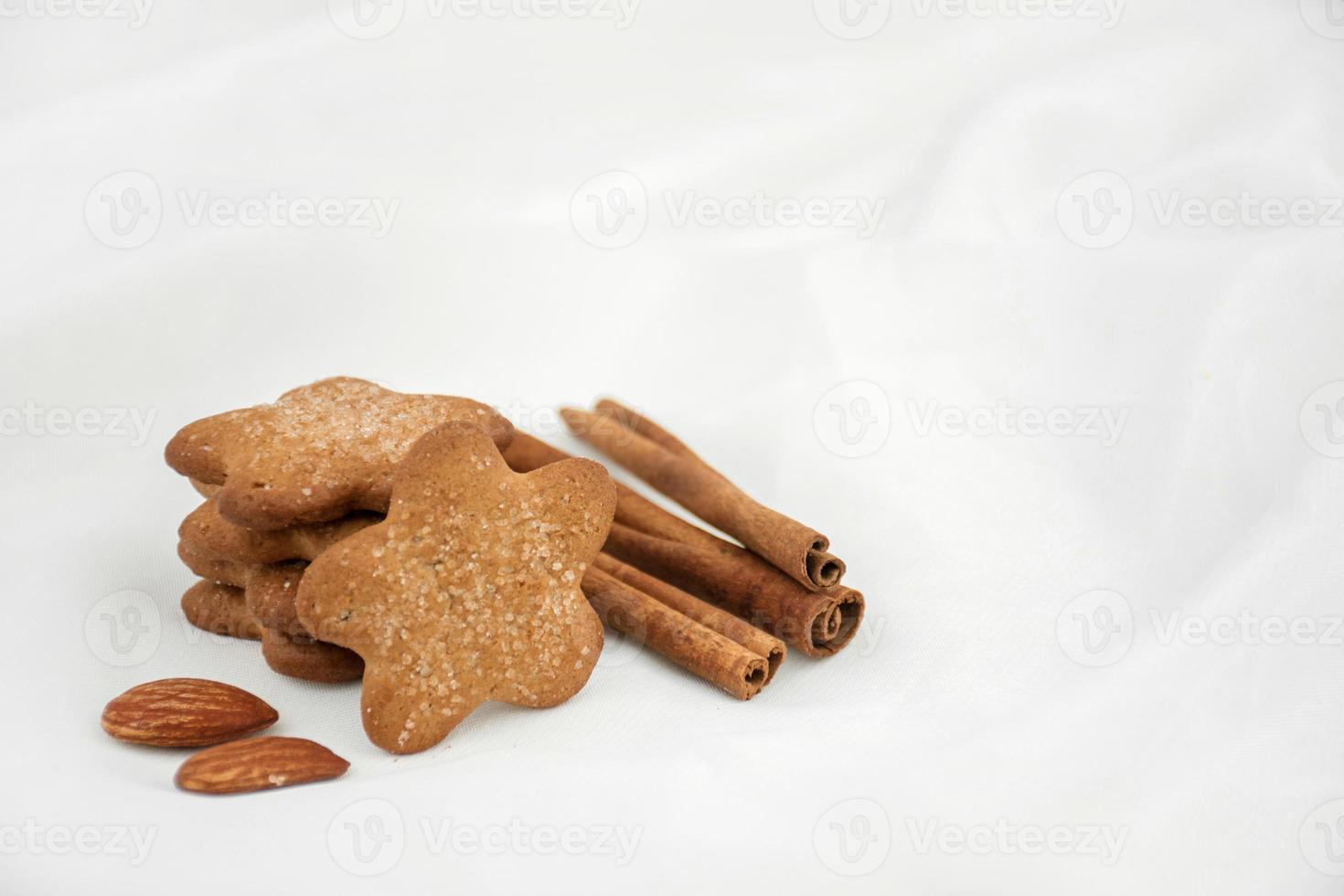 Ginger star cookies with sugar, cinnamon and almonds on a white blurred background. Christmas recipe photo