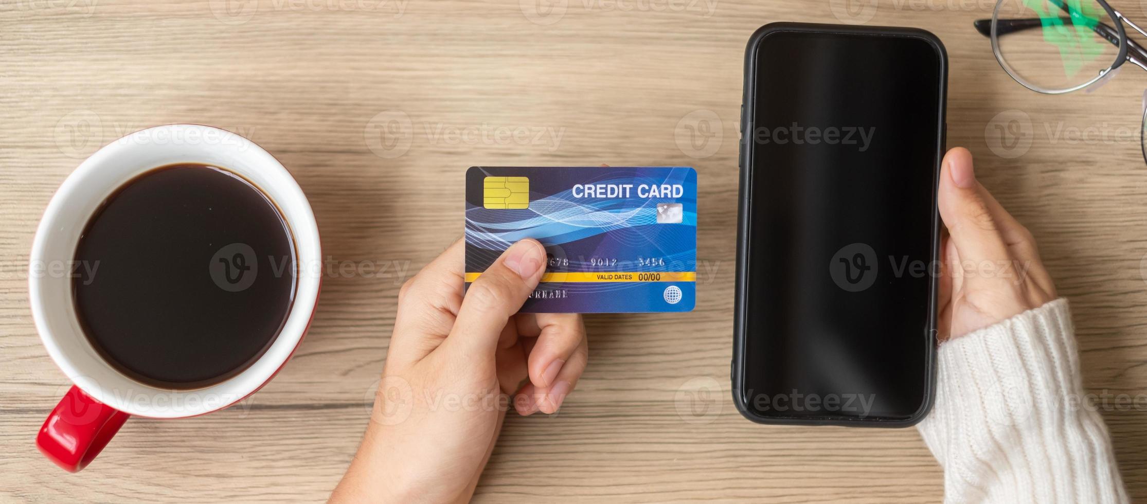 Hand holding credit card for online shopping on smartphone during drinking coffee. Merry Christmas eve, December, seasonal, Black Friday sale, New Year and holiday concept photo