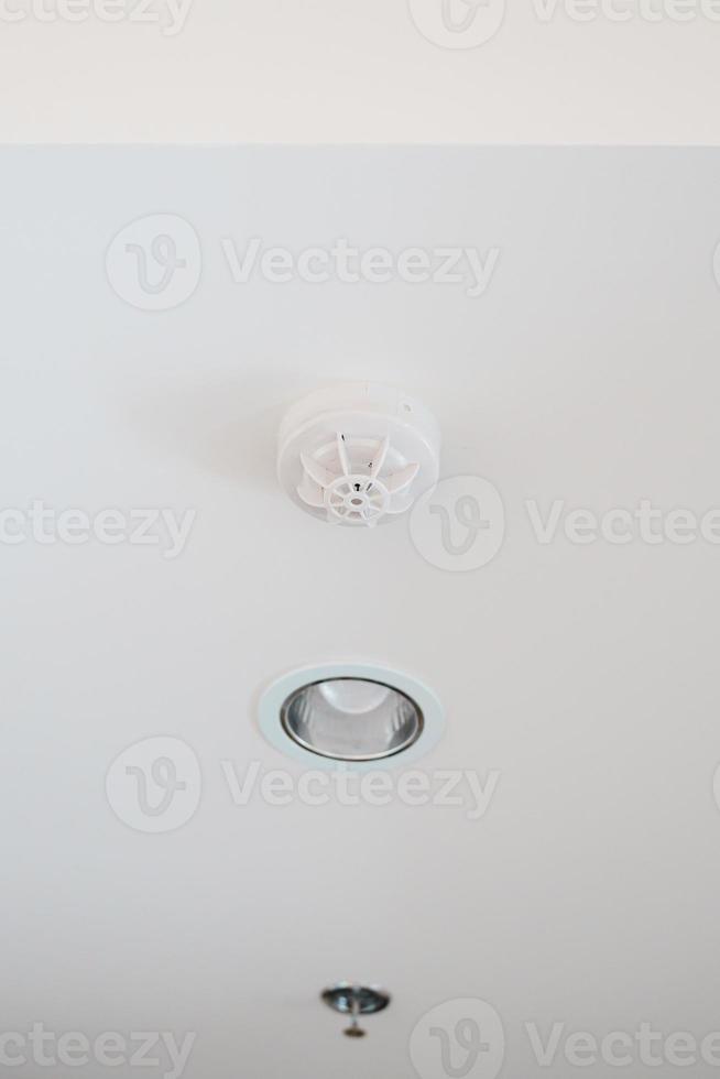 Smoke sensor detector mounted on roof in home or apartment. Safety and conflagration security concept photo